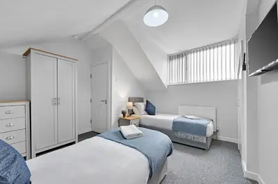 a white bedroom with two beds and a window at Kemble House - Air Host & Stay - 5 Bedroom, 5 Bathroom - Sleeping 10 in Prescot