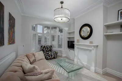 a living room with a couch and a clock on the wall at Blackpool Beauty! - Full House - Sleeps 9 in Blackpool