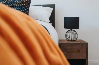 a person laying in a bed with a lamp on a night stand at Anfield Abode in Liverpool