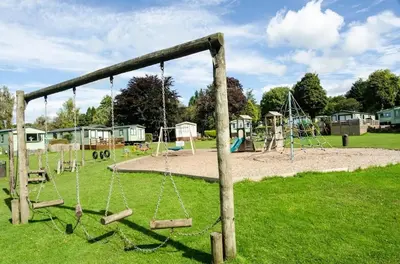 an empty playground with swings in a park at Woodland Camping Pod in Hale