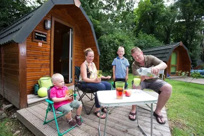 a family sitting at a table in front of a cabin at Woodland Camping Pod in Hale