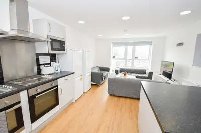 a kitchen and living room with a couch in the background at Spacious 6 Bedroom Apartment in Liverpool in Liverpool