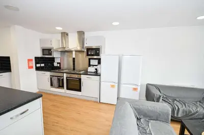 a kitchen with white appliances and a table and chairs at Spacious 6 Bedroom Apartment in Liverpool in Liverpool