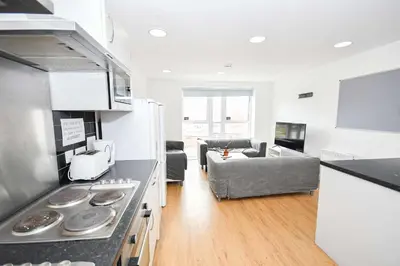 a kitchen and living room with a stove and a couch at Convenient 8 Bedroom Apartment in Liverpool in Liverpool