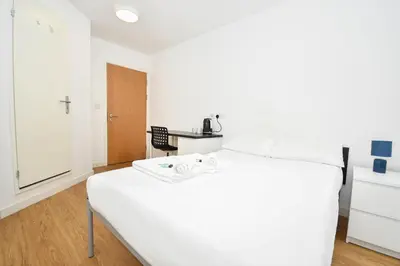 a white bed in a room with a table at Convenient 8 Bedroom Apartment in Liverpool in Liverpool
