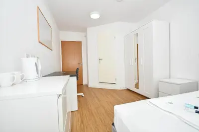 a white kitchen with white cabinets and a wooden floor at Convenient 8 Bedroom Apartment in Liverpool in Liverpool
