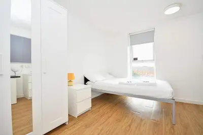 a white room with a bed and a window at Spacious 13 Bedroom Apartment in Liverpool in Liverpool