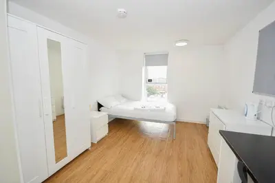 a white room with a bed and a window at Spacious 13 Bedroom Apartment in Liverpool in Liverpool