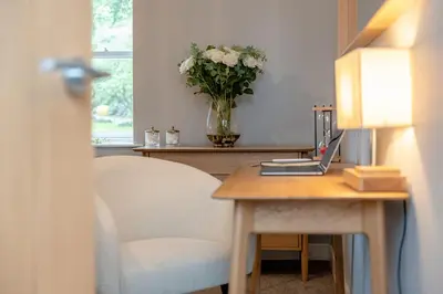 a desk with a vase of flowers and a table with a chair at Parson Castle View, Sleeps 6, Clitheroe Centre in Clitheroe