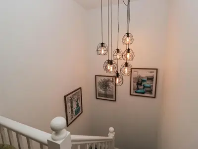 a room with a staircase with a chandelier at Holy Trinity Cottage in Millom