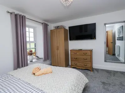 a bedroom with a bed with a television and a dresser at Holy Trinity Cottage in Millom
