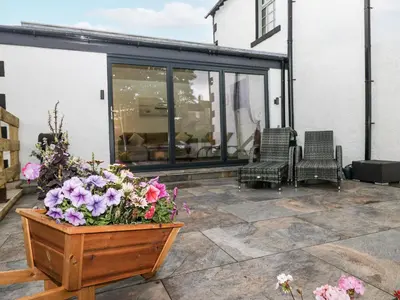 a patio with chairs and flowers in a wooden box at Holy Trinity Cottage in Millom