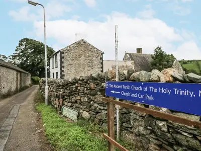 a sign in front of a stone wall at Holy Trinity Cottage in Millom