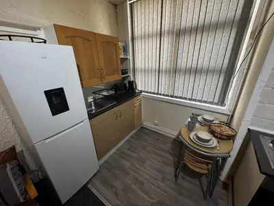 a small kitchen with a table and a refrigerator at Ground Floor Cute & Cozy - 1 Person Studio - South Pier in Blackpool