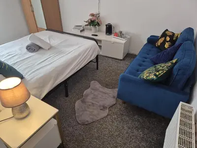 a bedroom with a bed and a blue couch at New Central Guest House in Blackpool