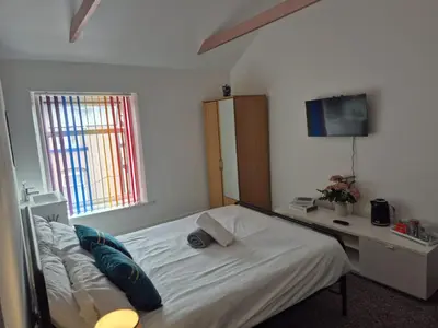 a bedroom with a bed and a desk and a television at New Central Guest House in Blackpool