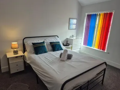 a bedroom with a white bed with blue pillows and a window at New Central Guest House in Blackpool