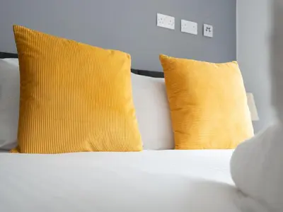 a white bed with two yellow pillows on it at Pass the Keys Stylish Flat Near Moorfields Stn in Liverpool
