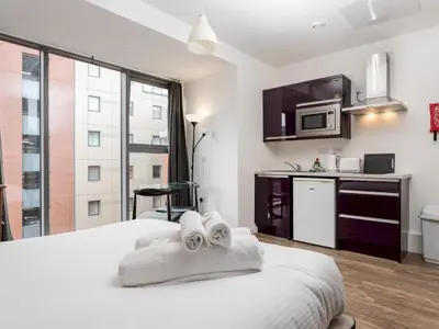 a hotel room with a bed with towels and a kitchen at Pass the Keys Stylish Flat Near Moorfields Stn in Liverpool