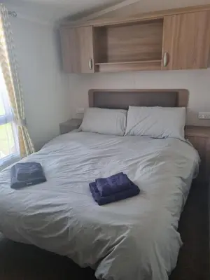 a large bed with two blue pillows on it at Leafy Lytham Holiday Home in Warton