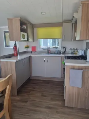 a kitchen with white cabinets and wooden floors at Leafy Lytham Holiday Home in Warton