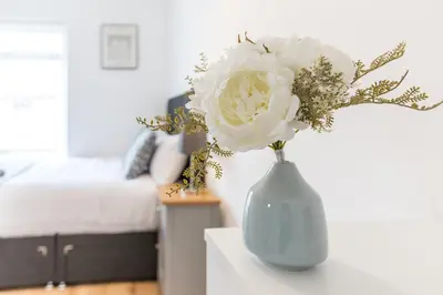a blue vase with white flowers on a table at Stylish 4 Bed House In Chorley in Chorley
