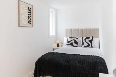 a white bedroom with a bed with a black blanket at Stylish 4 Bed House In Chorley in Chorley