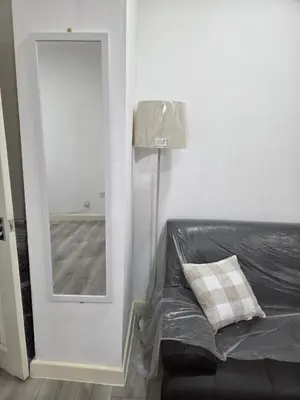 a room with a mirror and a couch and a lamp at Preston Studio Flat in Preston