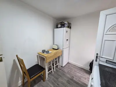 a small kitchen with a table and a refrigerator at Preston Studio Flat in Preston