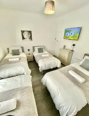a group of four beds in a room at stay anfield in Liverpool