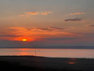 a sunset over a beach with the sun setting at Nettle Cottage in Heysham