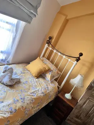 a bedroom with a bed and a lamp on a night stand at Nettle Cottage in Heysham
