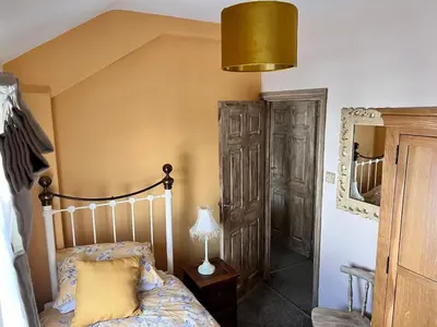 a bedroom with a bed and a lamp and a mirror at Nettle Cottage in Heysham