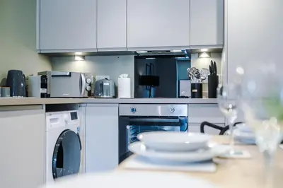 a kitchen with white cabinets and a table with dishes at High End 2 Bedroom with Parking and City Access in Liverpool