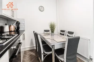 a kitchen with a table with chairs and a stove at 9 Guests, 4 Bedrooms, Modern Comfort in Bootle in Litherland