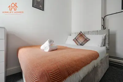 a bedroom with a bed with an orange blanket at 9 Guests, 4 Bedrooms, Modern Comfort in Bootle in Litherland