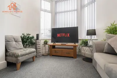 a living room with a television on a wooden table at 9 Guests, 4 Bedrooms, Modern Comfort in Bootle in Litherland