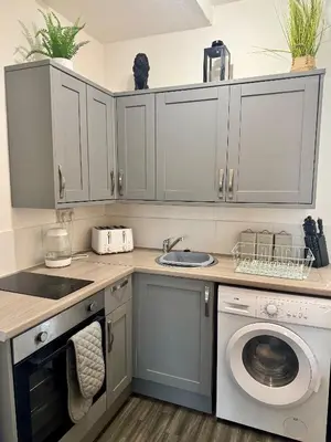 a kitchen with white cabinets and a washing machine at The Valley View Apartment in Great Harwood