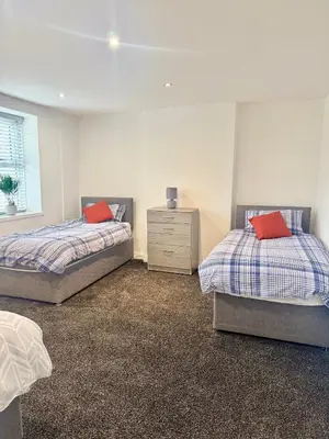two beds with red pillows in a bedroom at The Valley View Apartment in Great Harwood