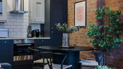 a kitchen with a table with chairs and a brick wall at Stylish Baltic Apt II, Parking, Sleeps 6! in Liverpool