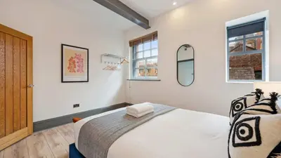 a bedroom with a large bed and two windows at Stylish Baltic Apt II, Parking, Sleeps 6! in Liverpool