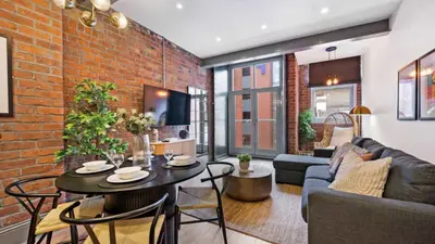 a living room with a table and a brick wall at Stylish Baltic Apt II, Parking, Sleeps 6! in Liverpool