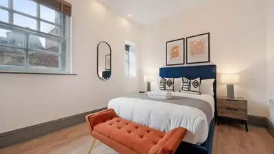 a bedroom with a large bed and a bench at Stylish Baltic Apt II, Parking, Sleeps 6! in Liverpool