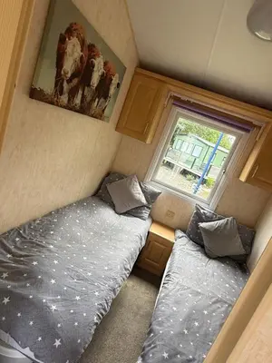 two beds in a small room with a window at Lake District Caravan Holiday in Millom