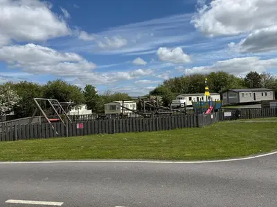a park with a fence and a playground at Lake District Caravan Holiday in Millom
