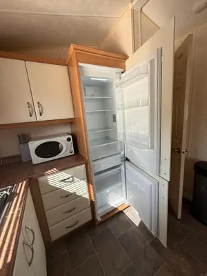 a kitchen with an empty refrigerator with a microwave at Lake District Caravan Holiday in Millom