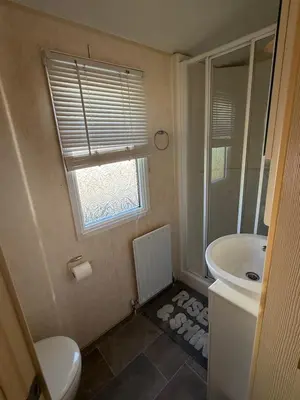 a bathroom with a toilet and a sink and a window at Lake District Caravan Holiday in Millom