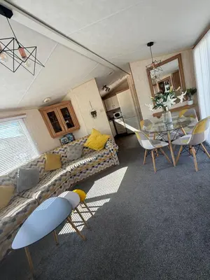 a living room with a couch and a table and chairs at Lake District Caravan Holiday in Millom