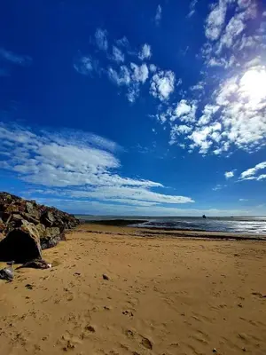 a beach with rocks and the ocean with a cloudy sky at Lake District Caravan Holiday in Millom