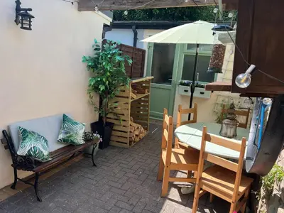 a patio with a table and chairs and an umbrella at Historic 1600’s The Grocer’s Cottage in Heysham